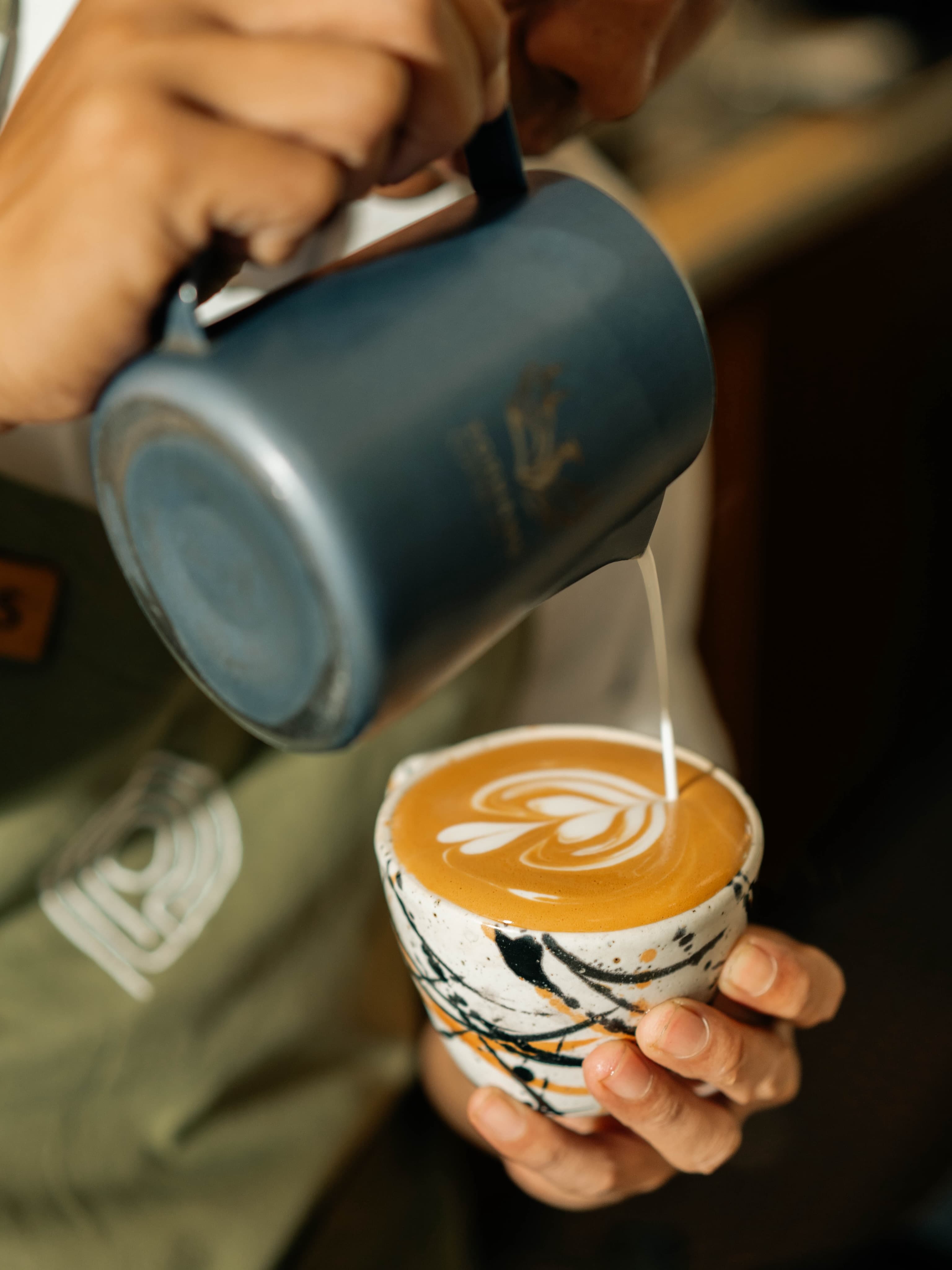 Barista menuangkan susu untuk membuat latte art